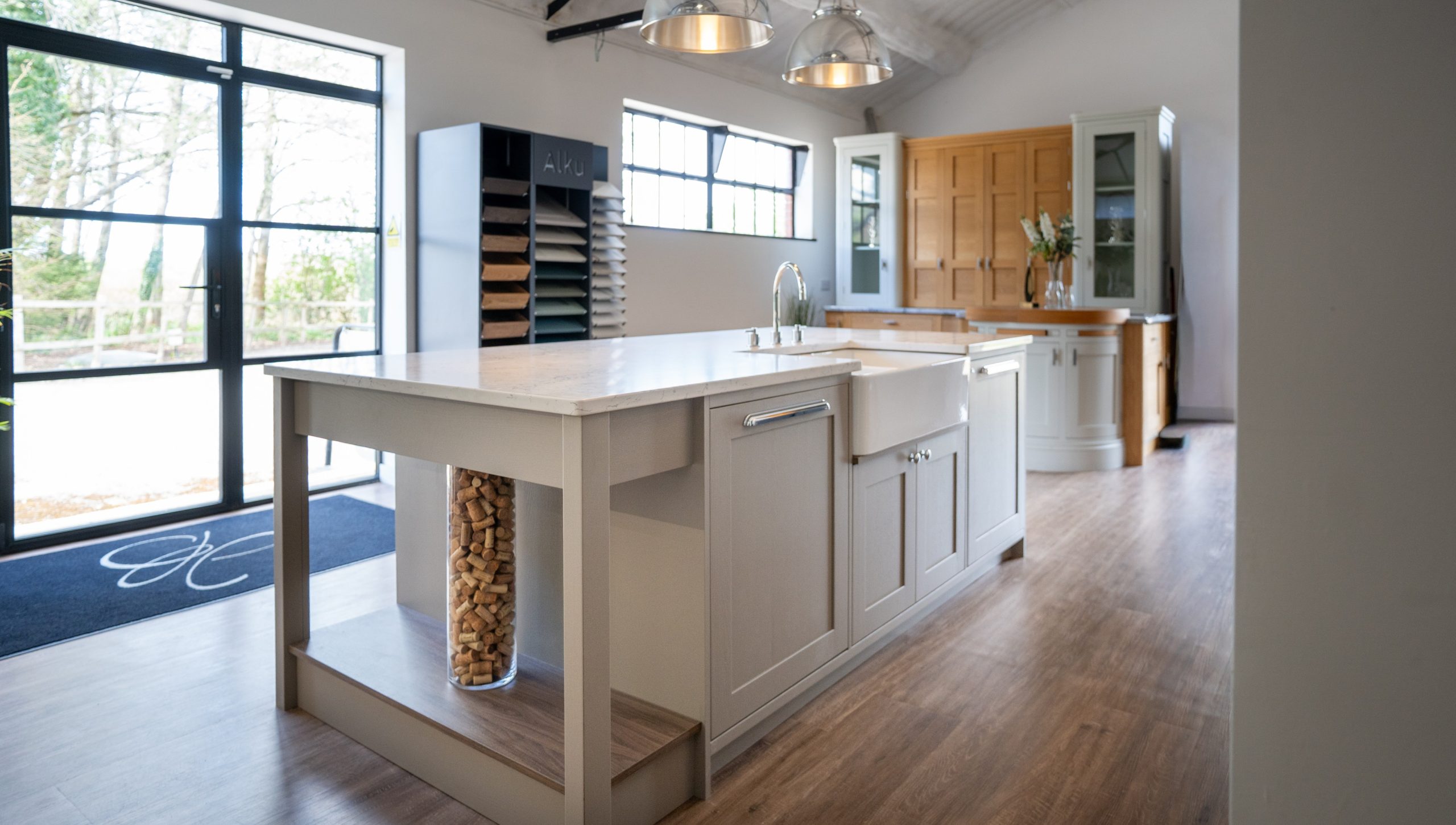 Shaker-style kitchen showroom display at Jones Britain, Tunbridge Wells, featuring a painted island with marble worktop, Belfast sink, and worktop sample unit